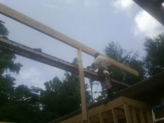 Carpenter setting a ridge beam over a new addition frame — Ice Dam Removal by Roofing Brothers in Malmo