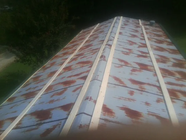 Rusted metal roof panels with new wood purlins before replacement — Storm Damage Roof Repair in Malmo by Roofing Brothers