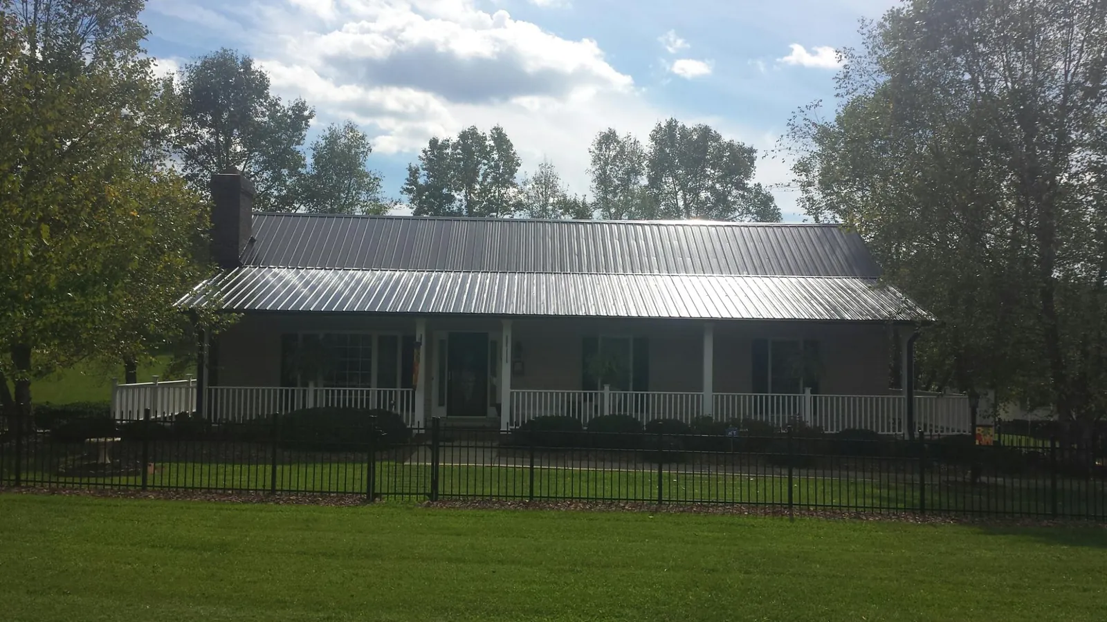 Gray metal roof on a brick ranch with a full width front porch — Gutter Guard Installation work by our crew in Malmo