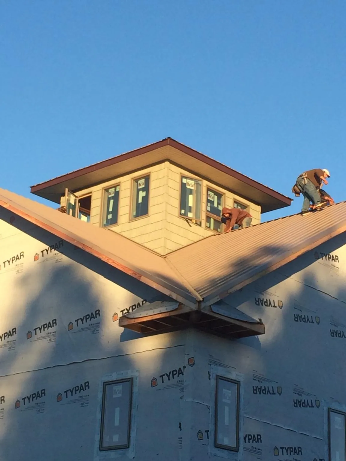 Roofers working around a rooftop cupola on a new metal roof at sunset — Roof Waterproofing in Malmo by Roofing Brothers